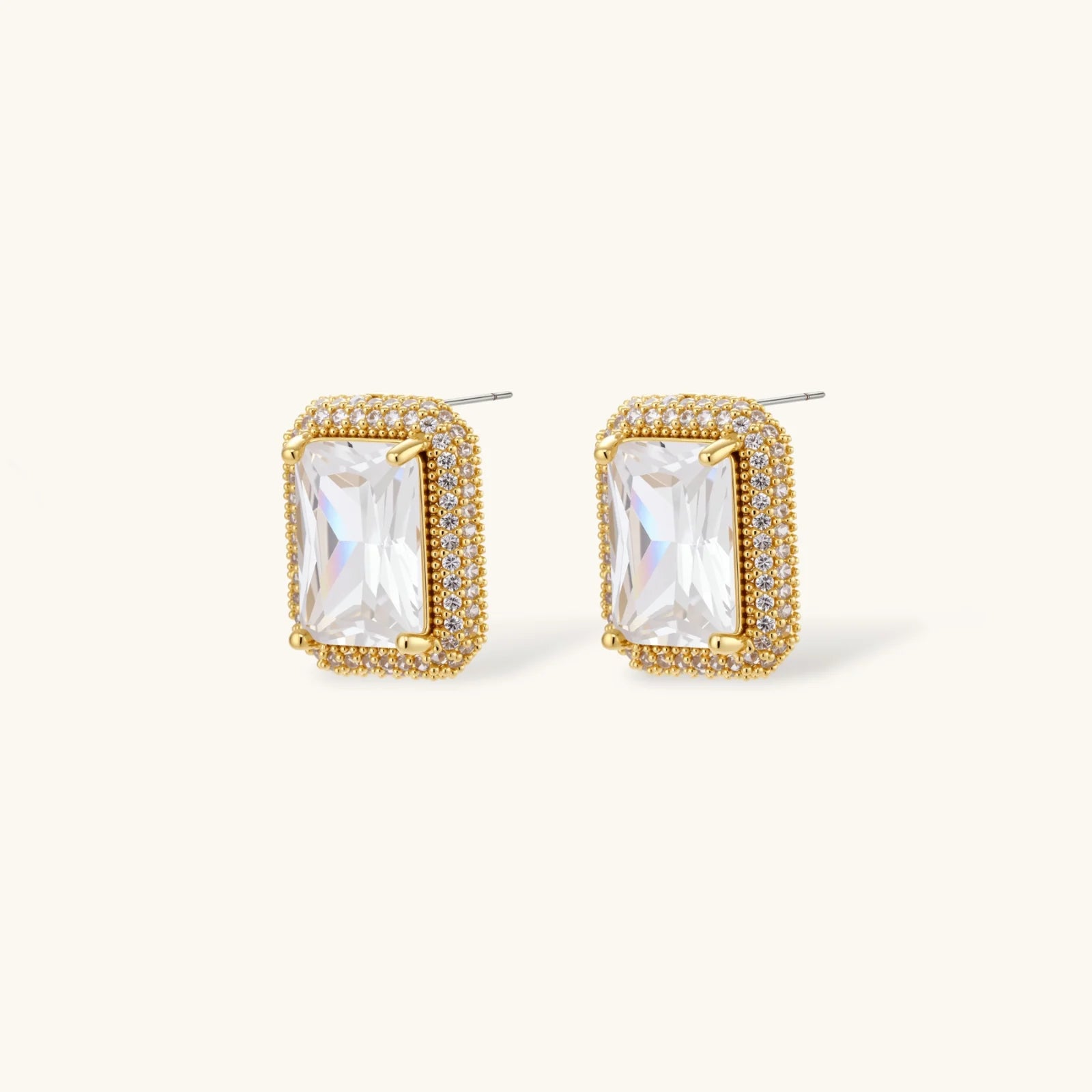 Gold-plated jewelry set with rectangular cubic zirconia stones in pave halo settings on cream background