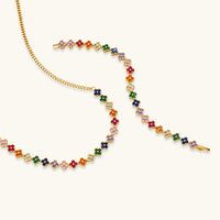 Colorful four-leaf clover jewelry set with rainbow cubic zirconia stones in gold-plated setting on white background