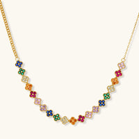 Colorful four-leaf clover jewelry set with rainbow cubic zirconia stones in gold-plated setting on white background