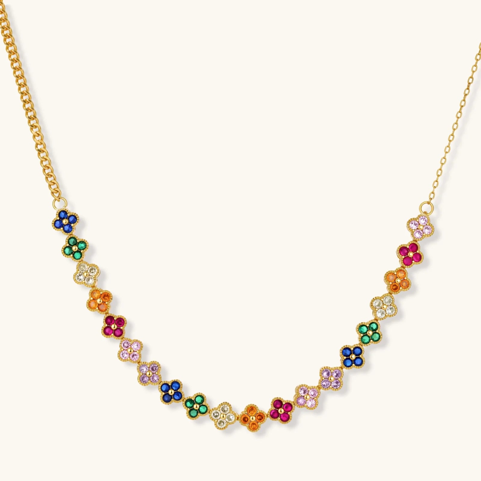 Colorful four-leaf clover jewelry set with rainbow cubic zirconia stones in gold-plated setting on white background