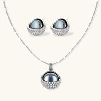 Elegant spherical pendant necklace and earrings set featuring crystal-pavé bottom half in gold or silver finish on white background.
