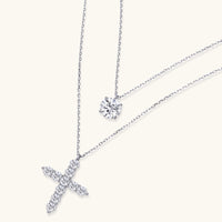 Two delicate sterling silver necklaces with moissanite stones - one solitaire pendant and one cross pendant on white background.