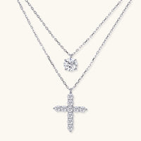 Two delicate sterling silver necklaces with moissanite stones - one solitaire pendant and one cross pendant on white background.