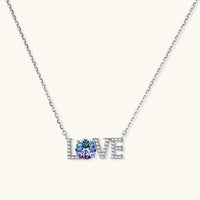 Sterling silver LOVE necklace with brilliant moissanite center stone and pavé details on neutral background.