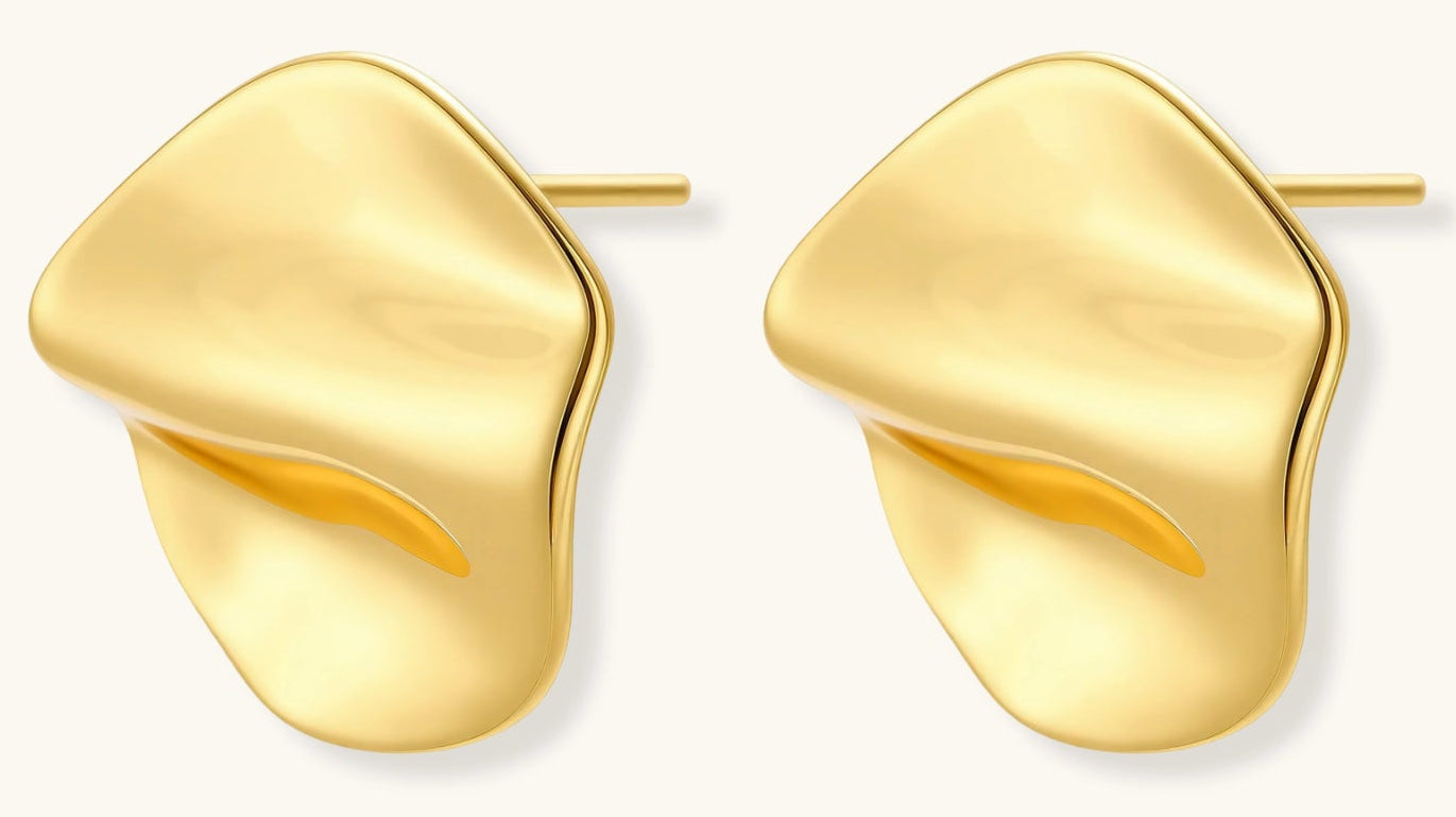 Close-up of organic gold-plated sterling silver stud earrings with flowing sculptural design and curved cut-outs