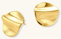 Close-up of organic gold-plated sterling silver stud earrings with flowing sculptural design and curved cut-outs