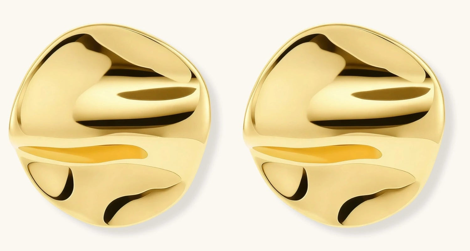 Close-up of organic gold-plated sterling silver stud earrings with flowing sculptural design and curved cut-outs
