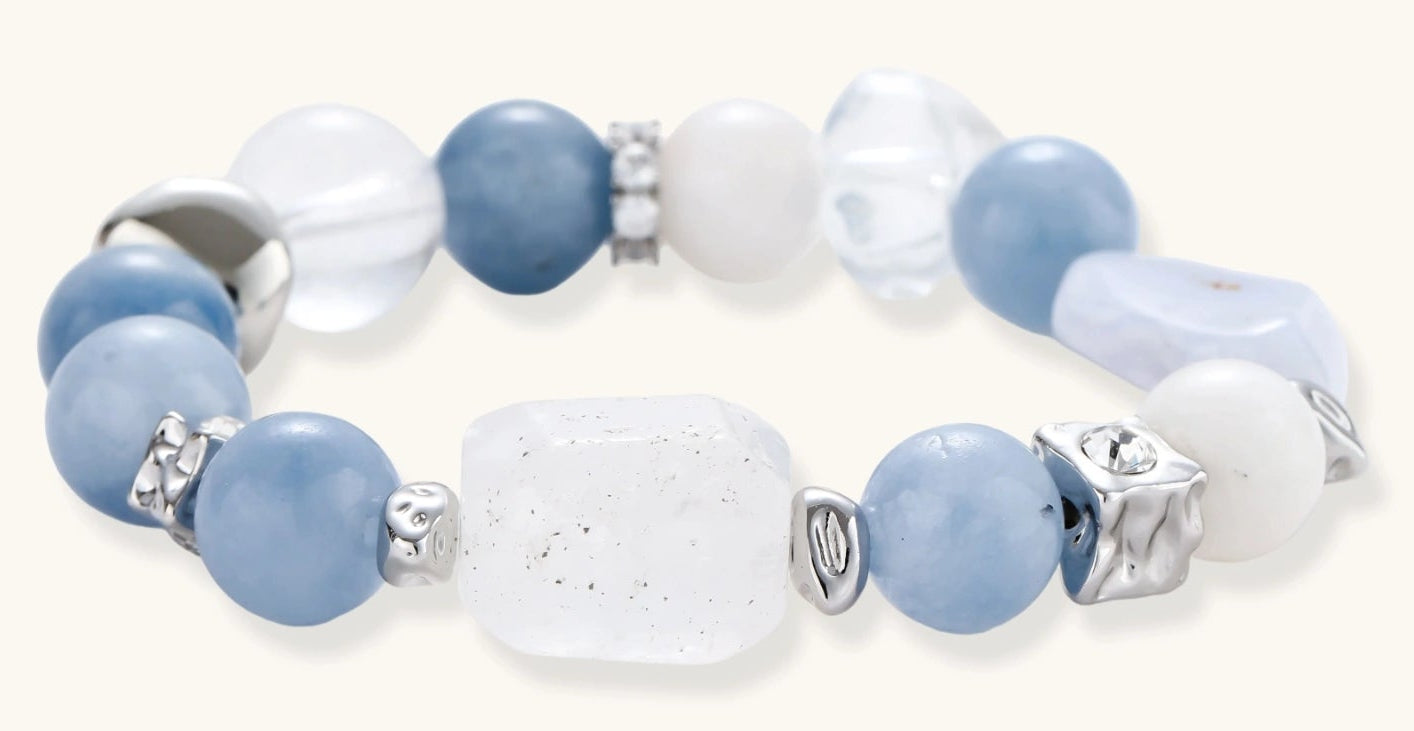 Stretchable bracelet with blue aquamarine beads, clear quartz crystals and copper accents on white background.