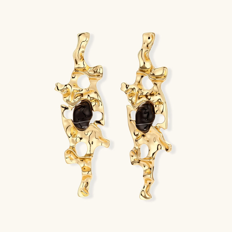 Elongated sculptural earrings with organic openwork design in eco-zinc alloy and dark resin accents on white background.