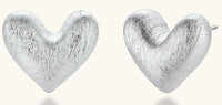 Pair of brushed platinum-plated 925 sterling silver puffy heart stud earrings on a cream background.