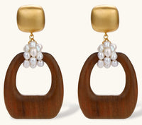 Gold-plated stud earrings with pearl clusters and organic brown wooden hoops on cream background