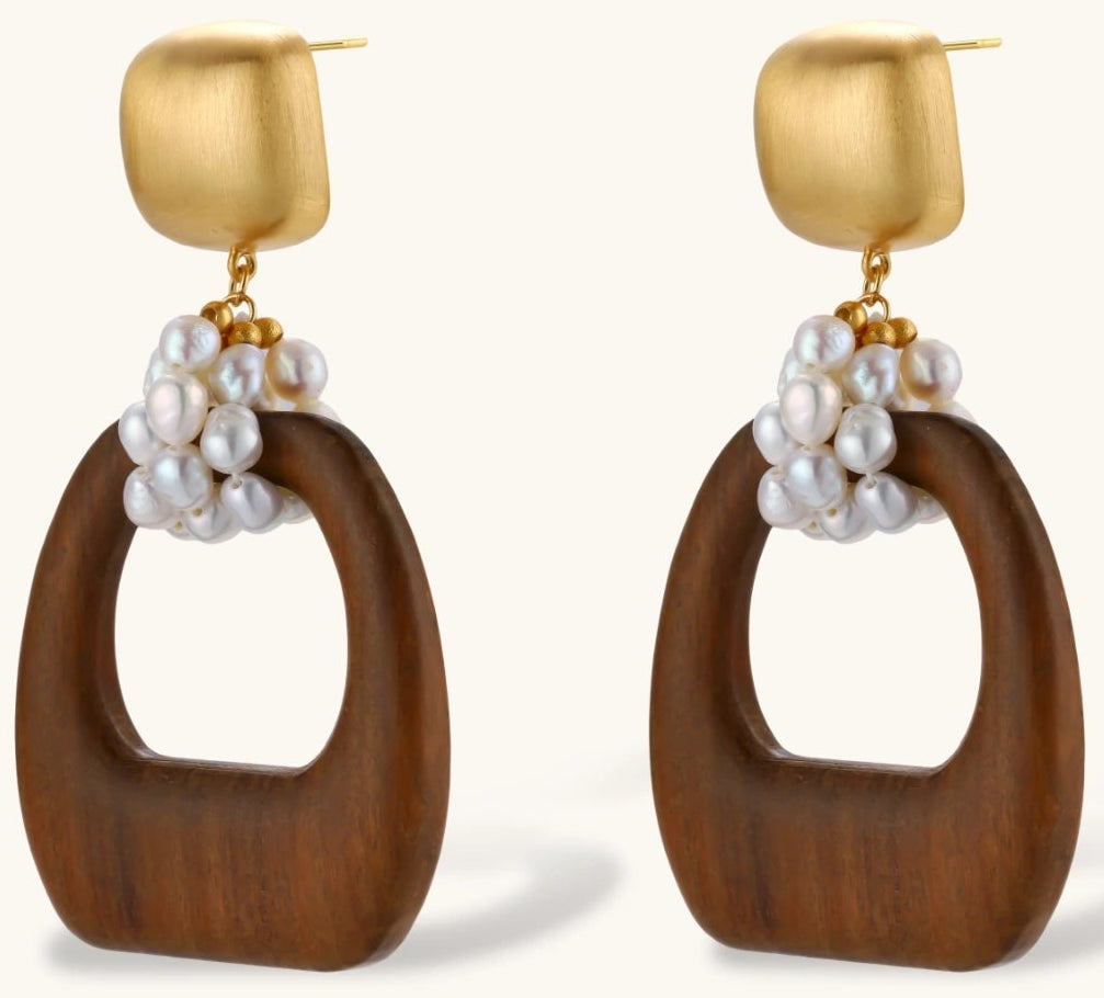 Gold-plated stud earrings with pearl clusters and organic brown wooden hoops on cream background