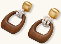 Gold-plated stud earrings with pearl clusters and organic brown wooden hoops on cream background