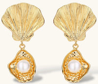 Gold shell-shaped drop earrings with scallop tops and oyster bottoms featuring round freshwater pearls on white background.