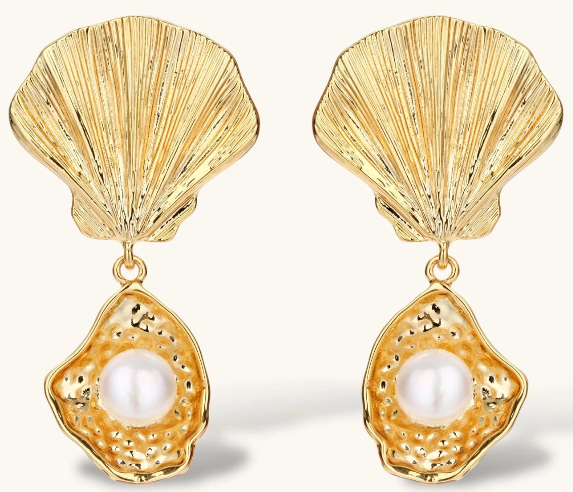 Gold shell-shaped drop earrings with scallop tops and oyster bottoms featuring round freshwater pearls on white background.