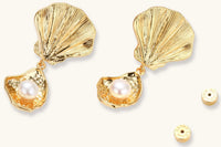 Gold shell-shaped drop earrings with scallop tops and oyster bottoms featuring round freshwater pearls on white background.