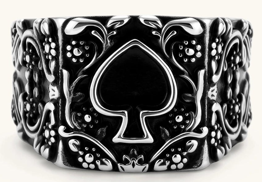 Silver-tone 316L stainless steel signet ring with black enamel spade motif and intricate floral scrollwork relief detail.