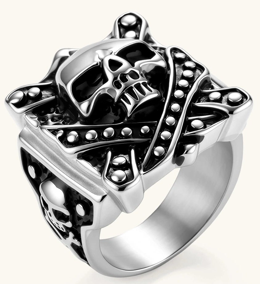 Silver-tone 316L stainless steel skull ring with crossbones, black enamel fill, studded details, and wide shank, 21mm top width.