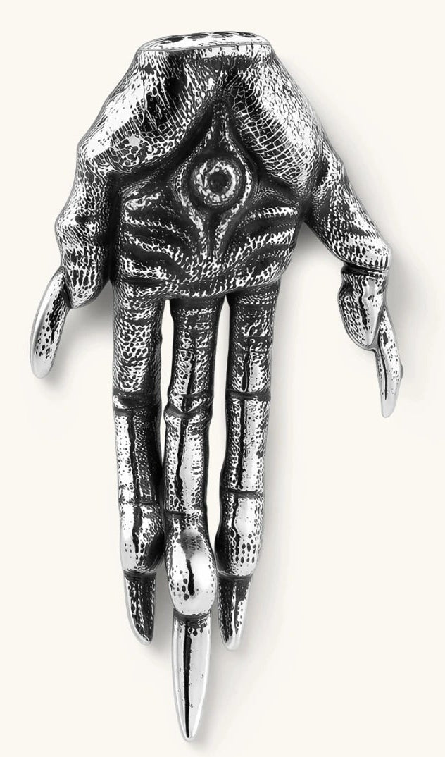 Silver stainless steel stud earring shaped like a skeletal demon claw hand with an eye motif on the palm and sharp talon fingers.
