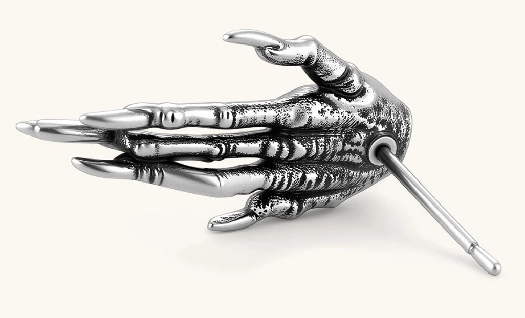 Silver stainless steel stud earring shaped like a skeletal demon claw hand with an eye motif on the palm and sharp talon fingers.