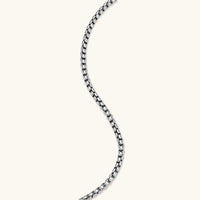 Silver stainless steel ankh pendant with skull motifs on vertical bar and textured ring top, on a box chain necklace.