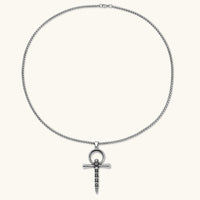 Silver stainless steel ankh pendant with skull motifs on vertical bar and textured ring top, on a box chain necklace.
