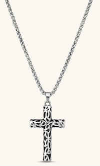 Silver stainless steel Celtic cross pendant with filigree vine pattern on a box chain, against a cream background.