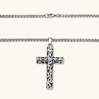 Silver stainless steel Celtic cross pendant with filigree vine pattern on a box chain, against a cream background.