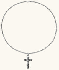 Silver stainless steel Celtic cross pendant with filigree vine pattern on a box chain, against a cream background.