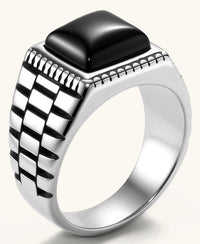 Silver stainless steel signet ring with checkered band texture, beaded border, and square black onyx cabochon stone center.