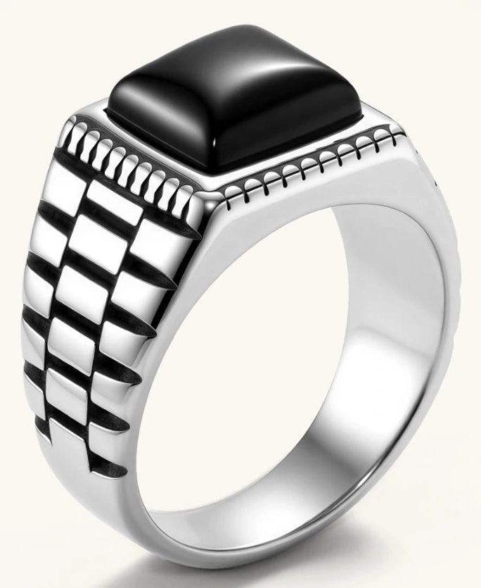 Silver stainless steel signet ring with checkered band texture, beaded border, and square black onyx cabochon stone center.
