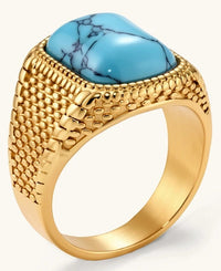 Gold PVD stainless steel signet ring with cushion faux turquoise stone and textured honeycomb band, front view.