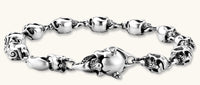 Sterling silver bracelet with linked skull motifs, decorative scroll engravings, and a large skull lobster-claw clasp.