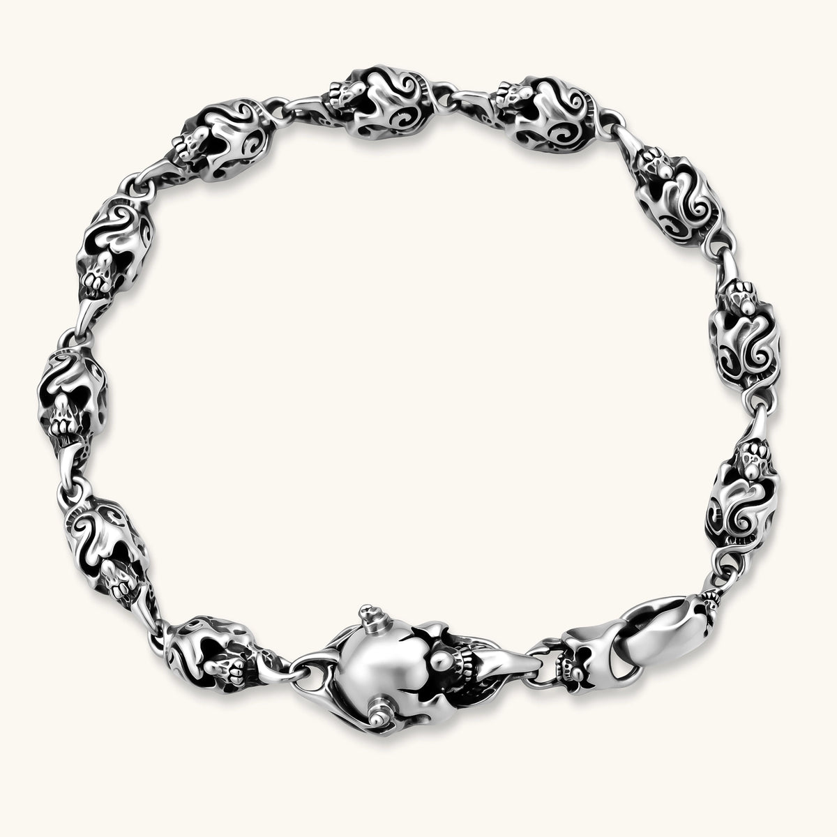 Sterling silver bracelet with linked skull motifs, decorative scroll engravings, and a large skull lobster-claw clasp.