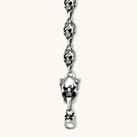 Sterling silver bracelet with linked skull motifs, decorative scroll engravings, and a large skull lobster-claw clasp.
