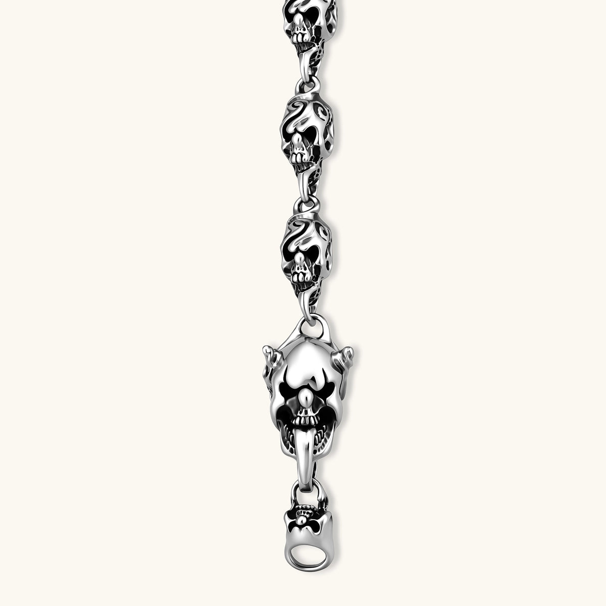 Sterling silver bracelet with linked skull motifs, decorative scroll engravings, and a large skull lobster-claw clasp.